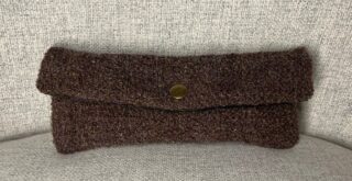 Porta occhiali in tessuto marrone trapuntato con chiusura di un bottone a pressione di colore ottone.